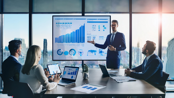 A startup founder presenting growth charts to venture capital investors in a modern office. The presentation includes data on business expansion, and investors are engaged with laptops and documents, discussing potential investment opportunities.