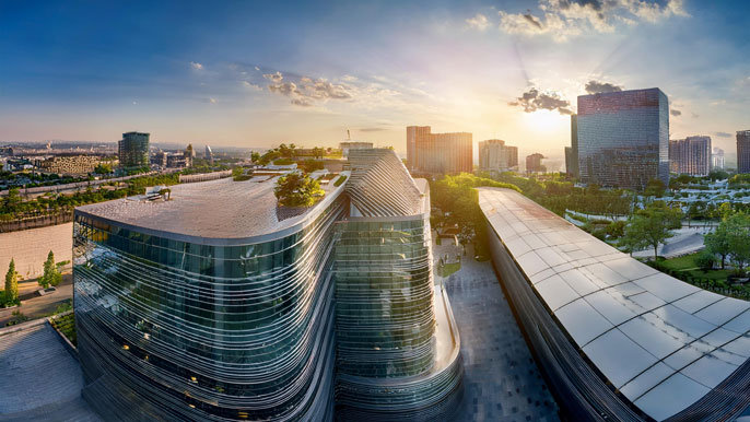 A modern urban skyline with sleek, glass-fronted retail buildings at sunrise, symbolizing commercial real estate growth.