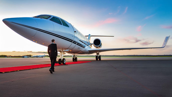 A sleek private business jet on a runway with an entrepreneur walking towards it on a red carpet, symbolizing luxury and efficiency in business travel.