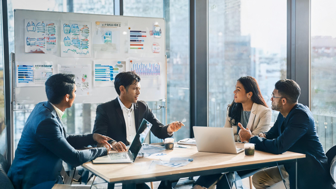 A group of founders and investors discussing startup equity in a modern office with charts showing company growth and equity distribution on the wall.