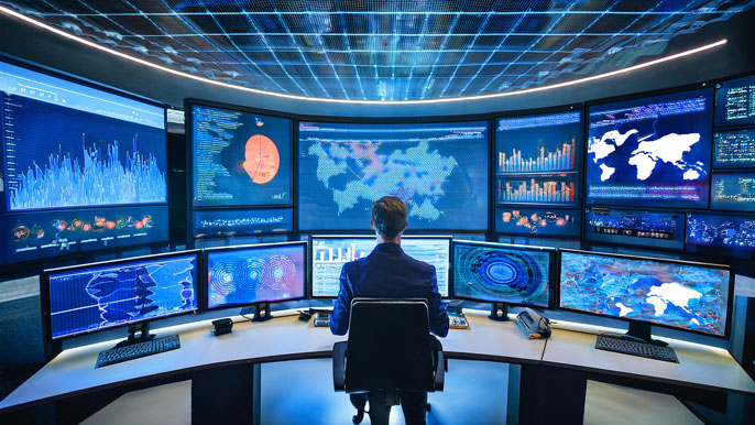 A control room with multiple screens displaying complex data patterns and graphs, representing NCAT algorithm data processing.