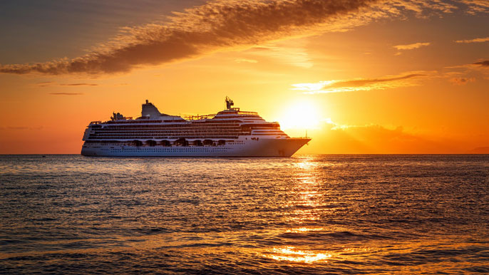 A cruise ship sailing at sunset, with golden skies and tranquil ocean waves, symbolizing Carnival Corporation's optimistic growth and global presence.