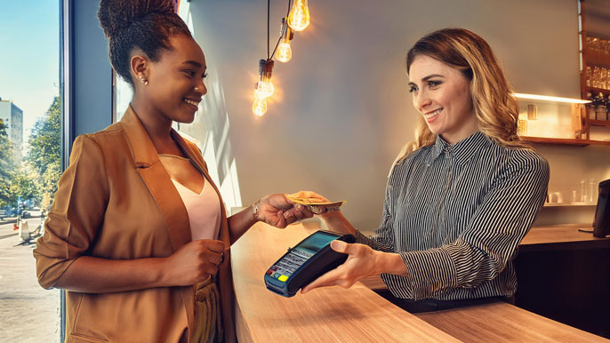 A customer making a cryptocurrency payment at a point-of-sale terminal, symbolizing mainstream crypto adoption in business transactions.