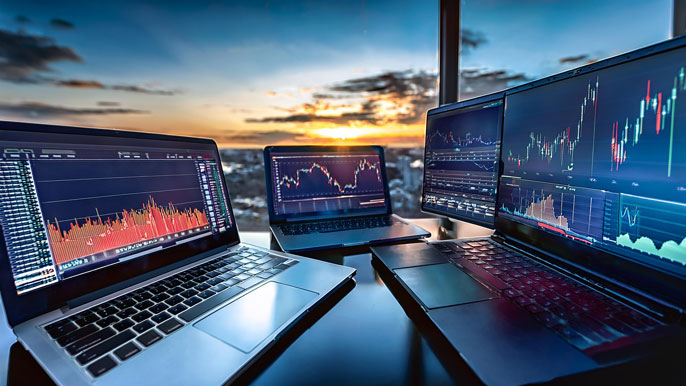 Multiple laptops displaying stock charts and trading platforms with real-time data, symbolizing the diverse tools and features offered by online stock brokers for efficient trading.