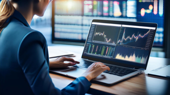 A financial analyst reviewing stock charts and performance data for key companies on a laptop screen, with graphs and stock tickers displayed. The background features large digital stock market displays, emphasizing detailed stock analysis.